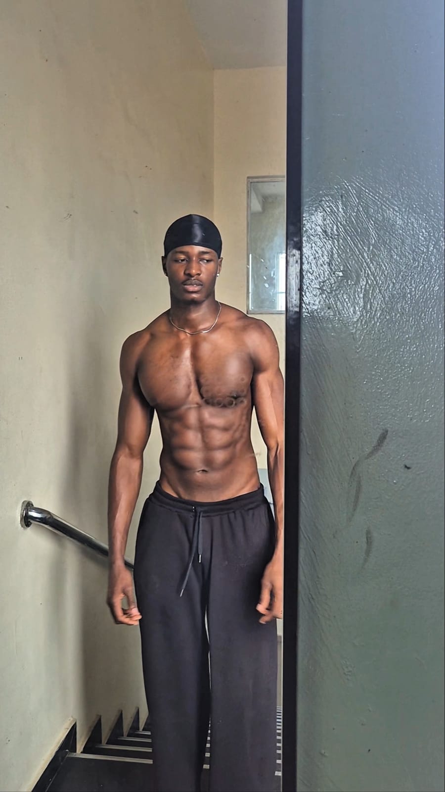 Maxi in a white tank and black trousers against a plain backdrop